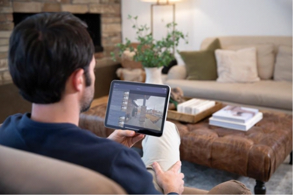 Man sitting in living room looking at home surveillance footage on his tablet. 