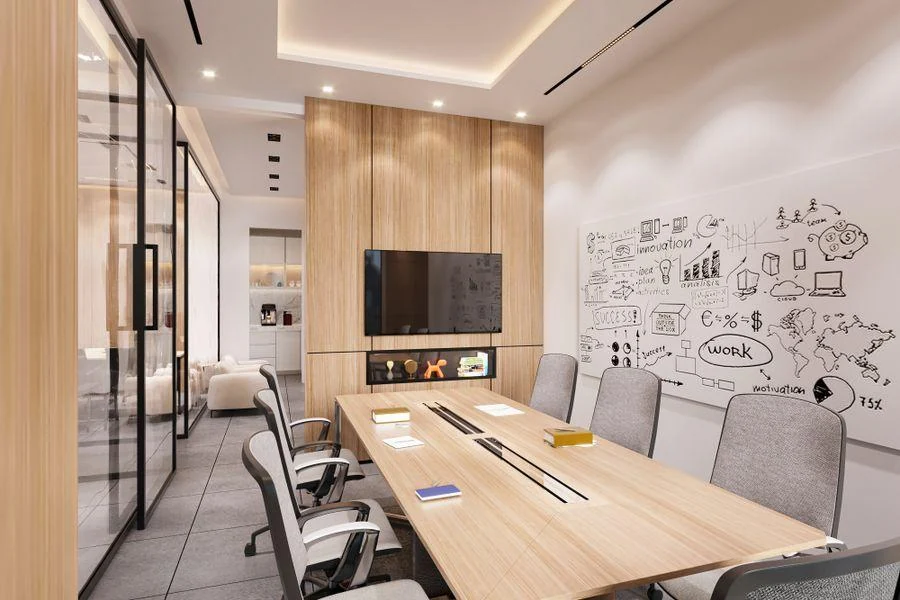 Modern conference room with a large table, wall-mounted display, glass partitions, and integrated architectural lighting.