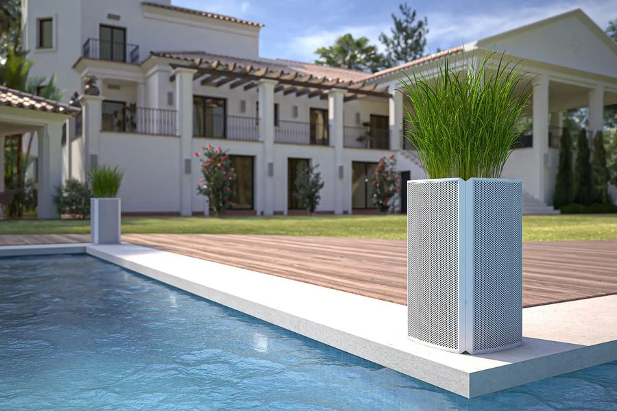 Luxury backyard pool with discreet Razor landscape speakers blending into modern planters outside an upscale contemporary home.