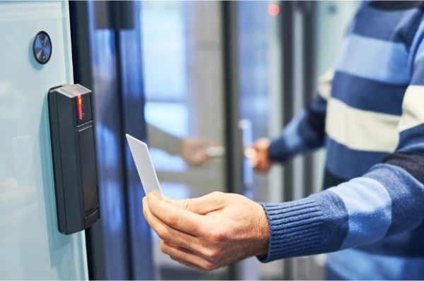 A close-up shot of a hand using a keycard at an access control keypad to unlock a secure door of a commercial building
